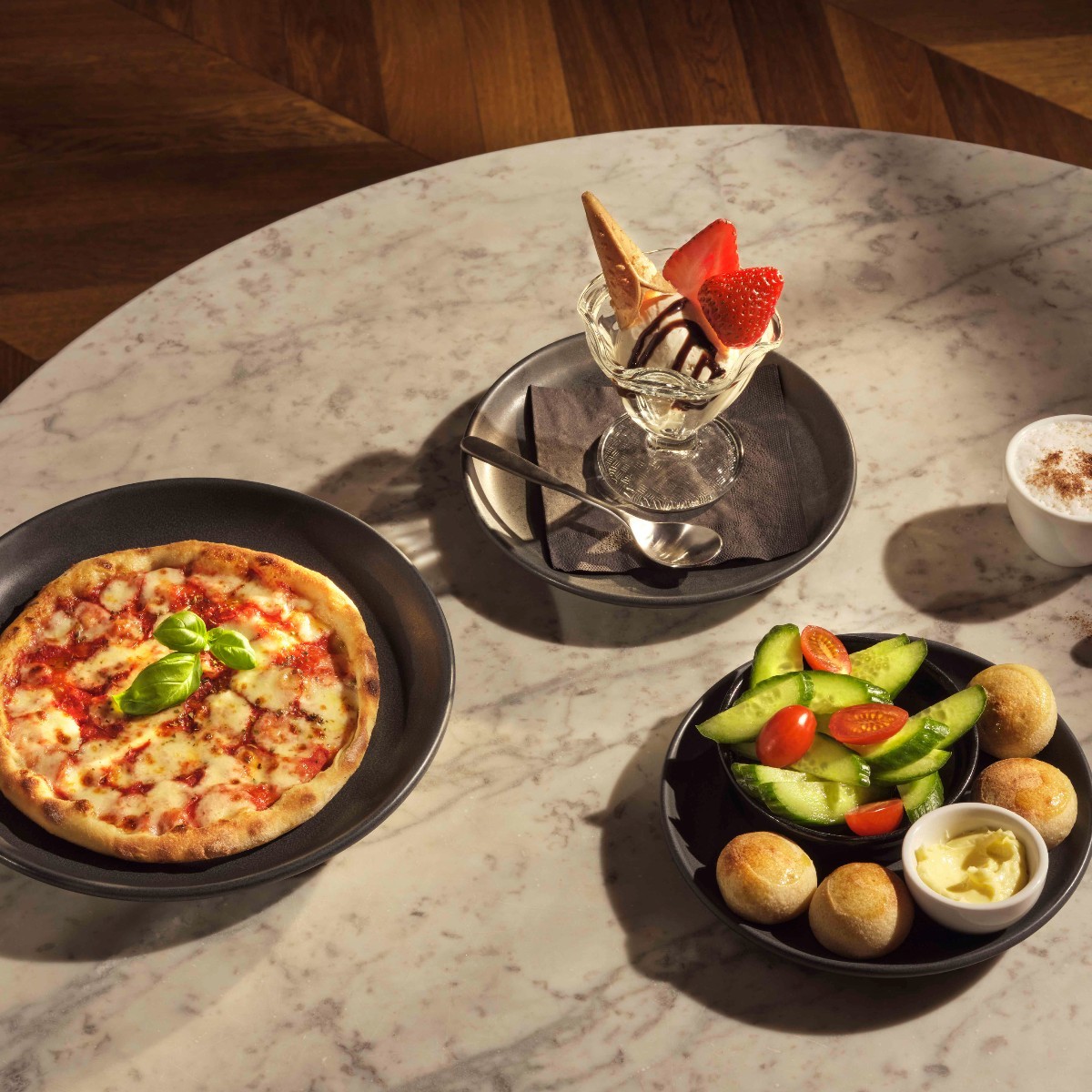 A pizza, dough balls and an ice cream on grey table